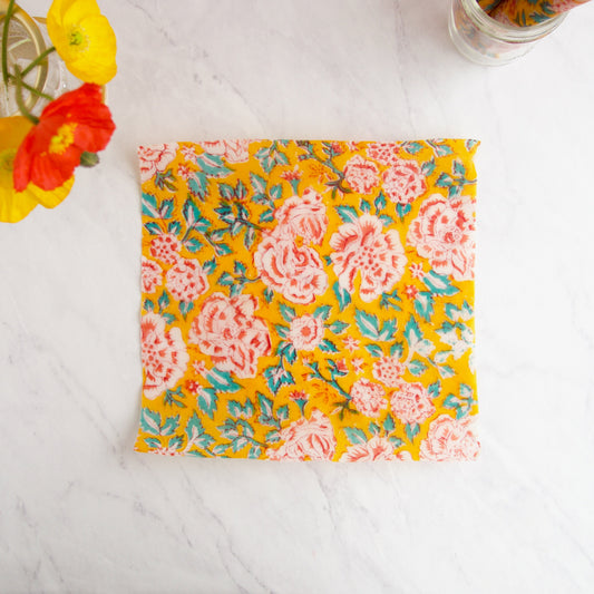 Beeswax food wrap in colorful floral print featuring red and white chrysanthemums on an orange background